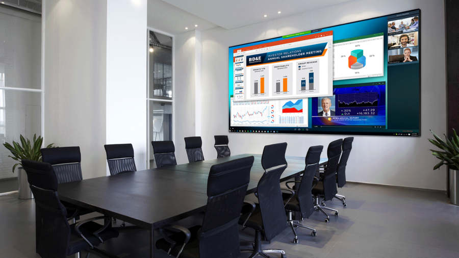 A modern conference room with a large video display sharing graphs, charts, and a virtual call. 