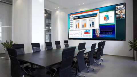 A modern conference room with a large video display sharing graphs, charts, and a virtual call. 