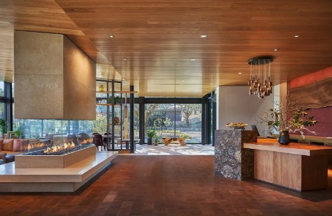 A spacious, modern home with a wood-paneled ceiling, glass fireplace, and luxury lighting design. 