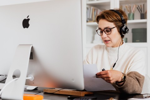Woman sitting at desk talking on the phone over a headset.