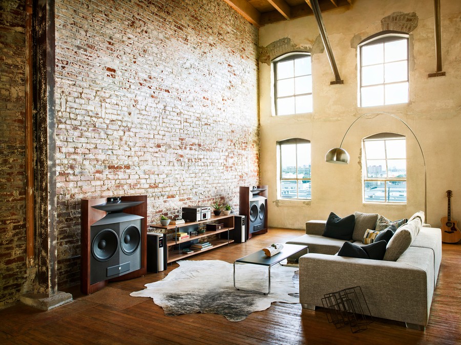 JBL high-end speakers in a loft room with tall ceilings and a brick wall.
