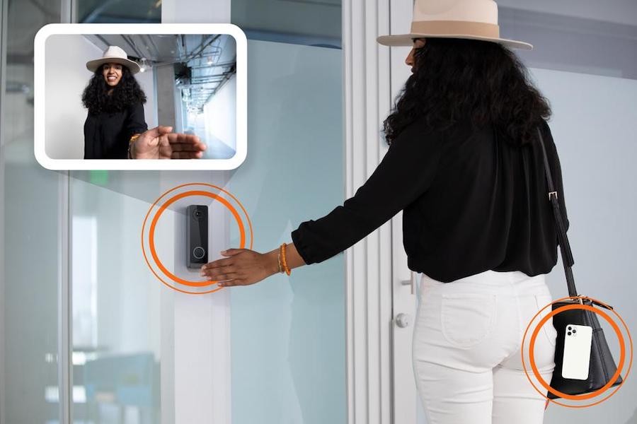 Woman waving her hand over an OpenPath access control reader to open the door.