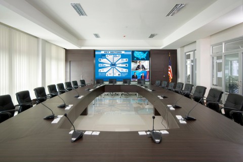 A large conference room with a square training table. Microphones are positioned at every seat.