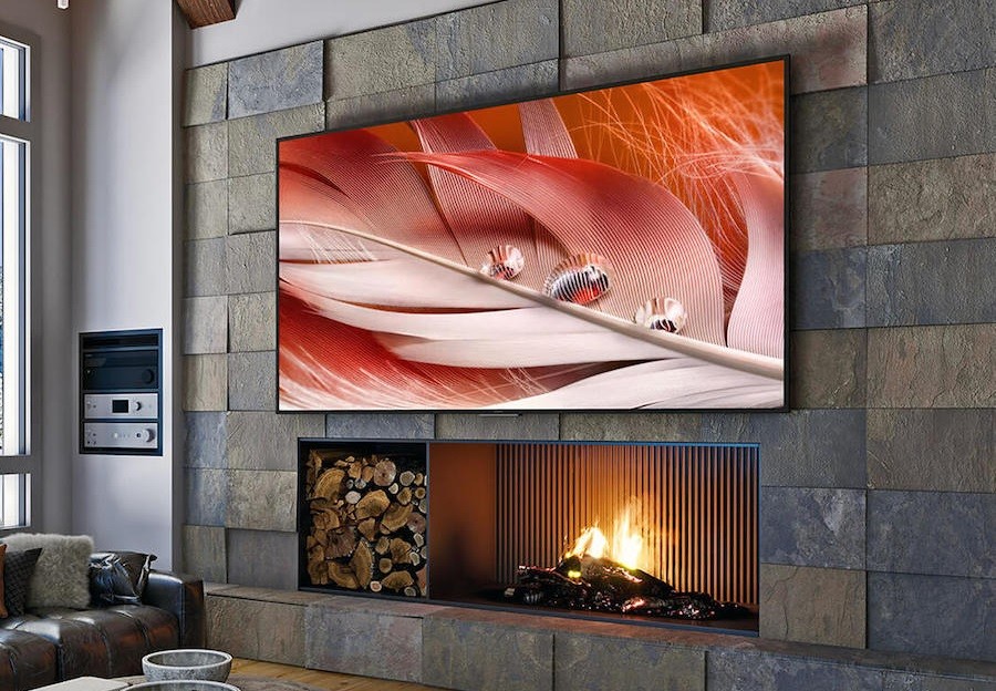 A living room with an in-wall fireplace and 100-inch Sony flat screen mounted above.