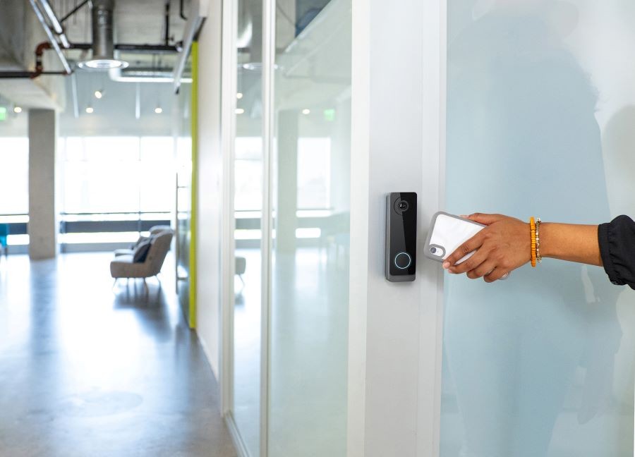 A person waving their smartphone in front of an access control device to gain entry.