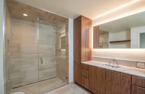 A bathroom with LED lighting strips along the ceiling and behind the mirror.