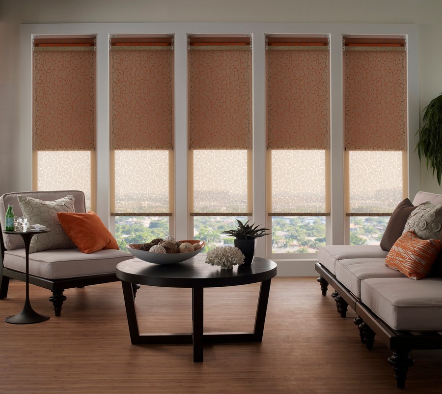 A living room with motorized shades lowered uniformly across five tall windows.