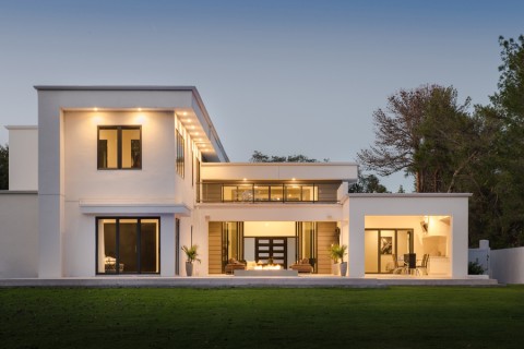 A modern, geometric house with warm landscape lighting