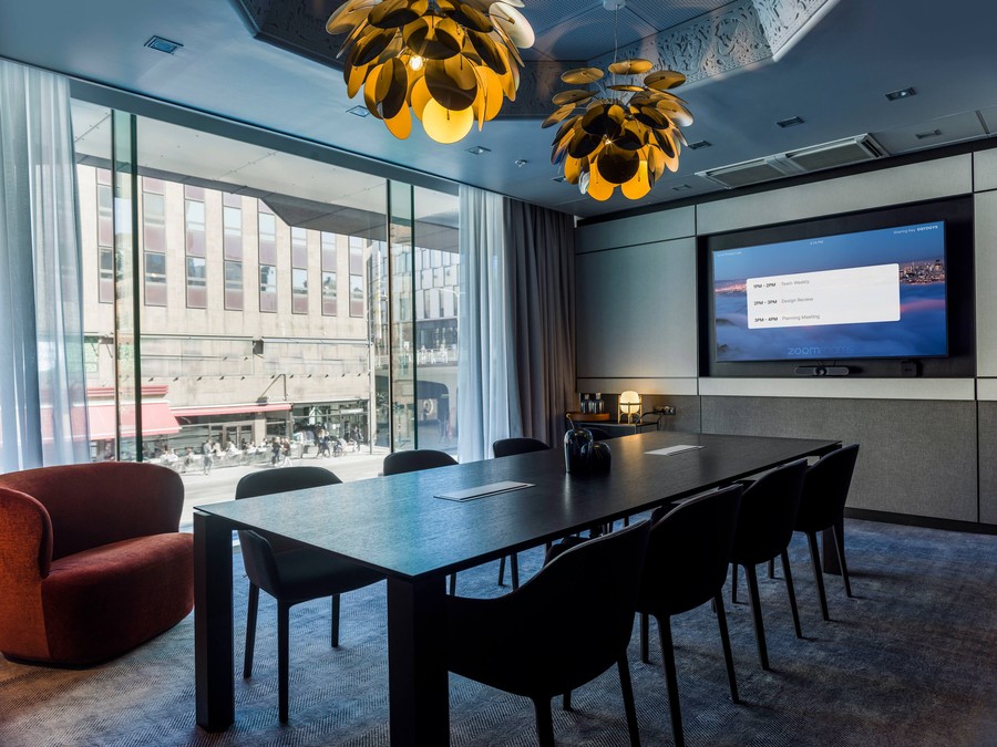 A hotel conference room with a video display on the wall and intricate light fixtures above.