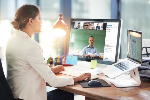 Woman sitting at desk with a digital workplace system on her laptop and desktop computer.