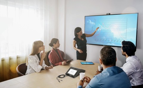 People in a conference room viewing a graph on a video display. 