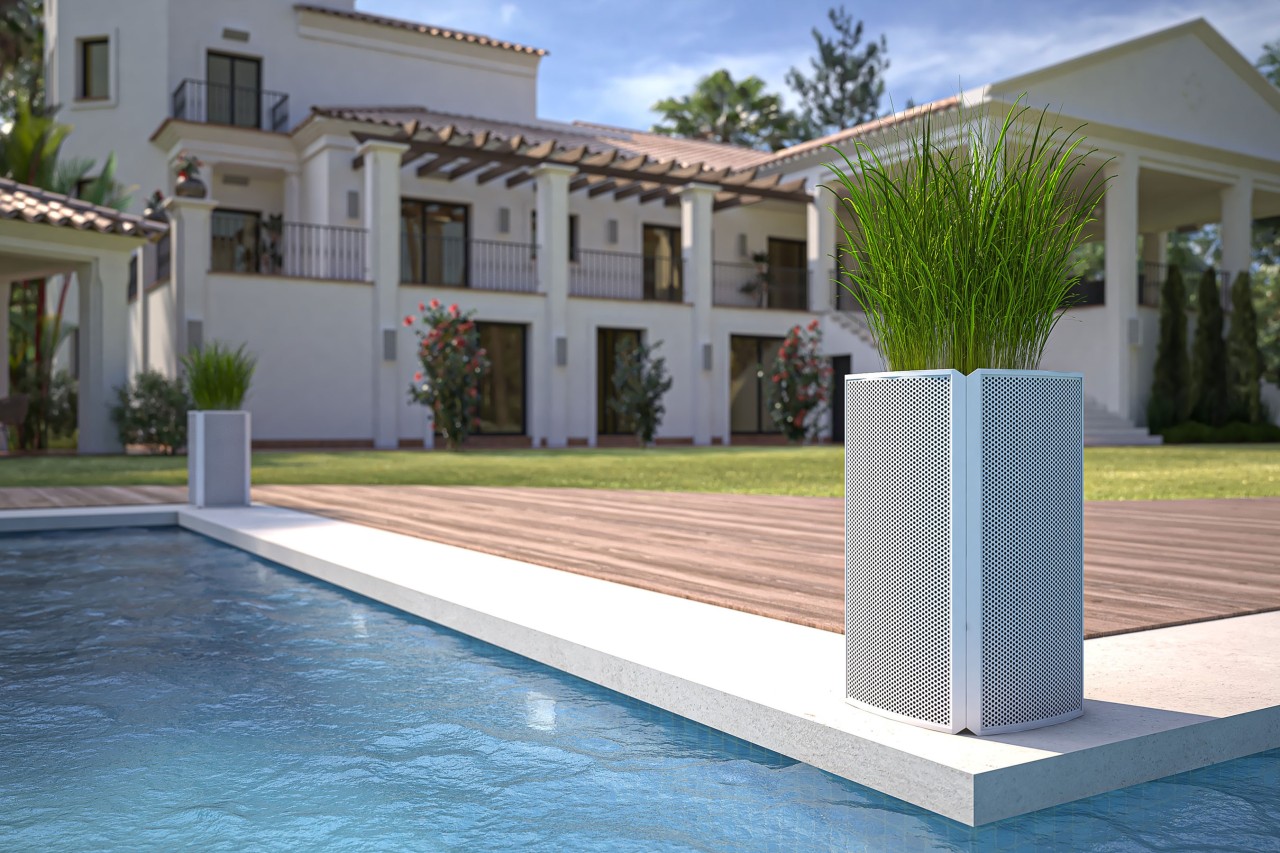 An in-ground pool with outdoor whole-home audio speakers installed by the water.