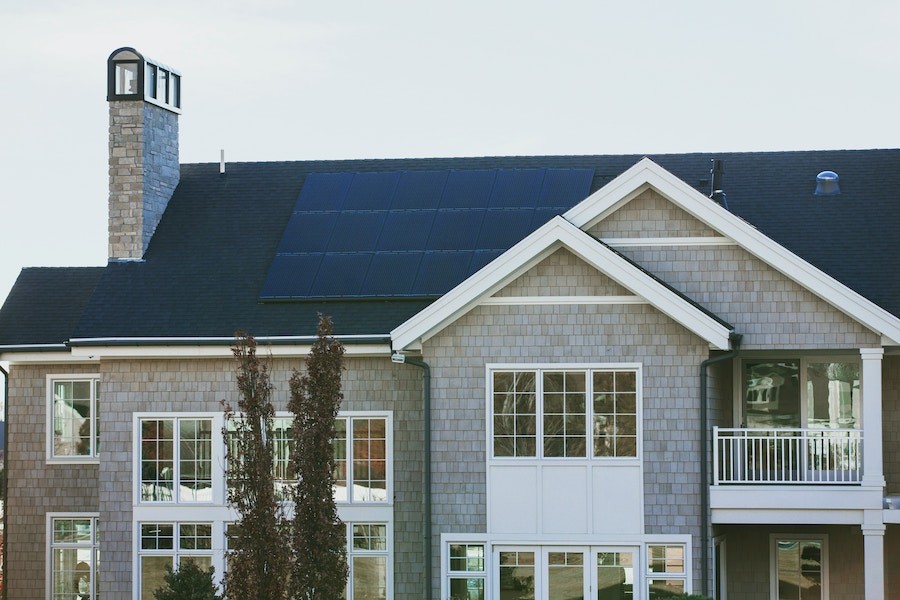 exterior view of a two-story home with solar panel grid installed on roof