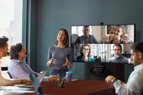 People in a collaboration space talking to four people over video conferencing on a flatscreen display.