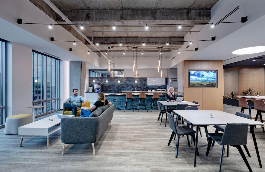 An office space with couches, tables, and a video display on the wall.