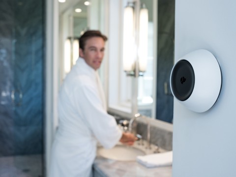 Man in a bathrobe in a bathroom talking to his Josh.ai home control device. 