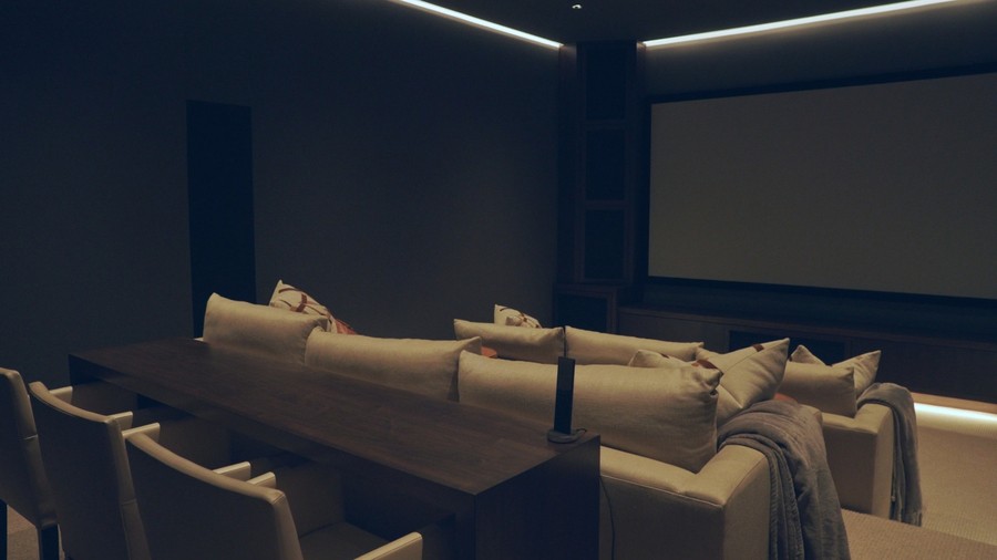 A luxury home theater with tiered seating and linear lighting.