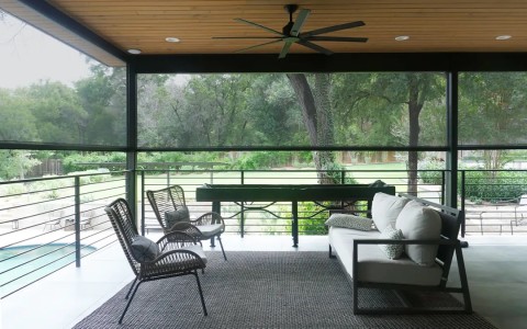 An outdoor living space with black outdoor motorized shades lowered.