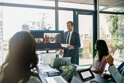 People in a conference room video conferencing with the Crestron Flex tabletop solution. 