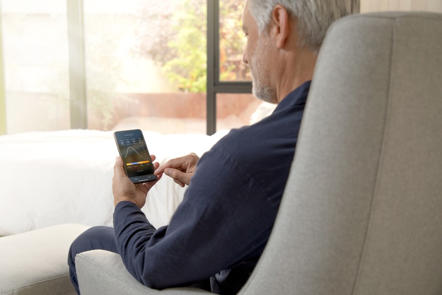 Man sitting in chair using Savant lighting control interface on his smartphone. 