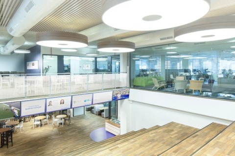 A business lobby with screens in front of stairs, a cafeteria downstairs, and several meeting rooms upstairs.
