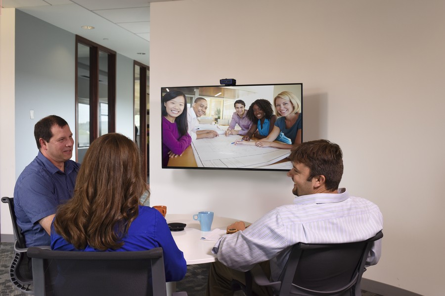 Three people participating in a video call in a huddle room. 