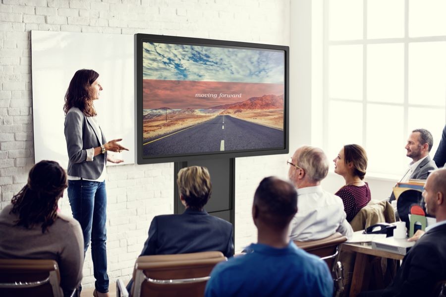 A woman in front of a display talking to a group of people.  