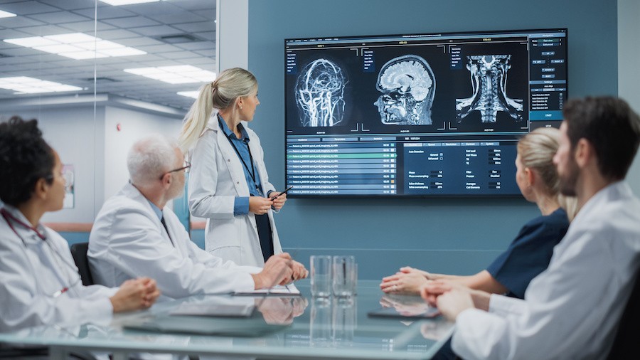 Doctors confer in a conference room equipped with advanced AV at a medical facility.