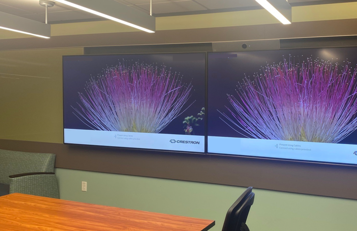 A conference or meeting space displaying a large screen at the front. Posters featuring children&rsquo;s imagery stand on either side of the screen, suggesting a child-focused event or presentation.